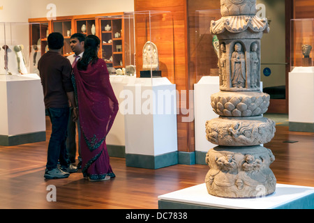 Couple indien parlant avec l'homme tout en observant l'artefact dans l'aile asiatique de Harn Museum,11ème et 12ème siècle la tour de Stupa en premier plan. Banque D'Images