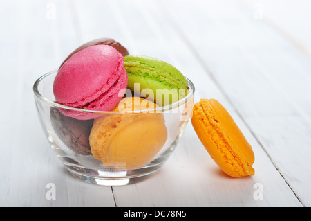 Macarons colorés dans bol en verre sur fond de bois Banque D'Images