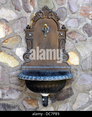 Belle fontaine de style ancien monté sur un mur de pierre Banque D'Images