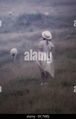 Une fille dans une robe vintage sur une prairie avec moutons Banque D'Images