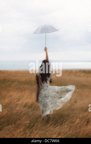 Une fille dans une robe à fleurs sur un champ avec un parasol Banque D'Images