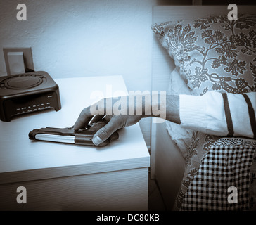 Artistique armé attaque main gauche au chevet chambre à coucher lit conceptuel le comportement de défense des armes à feu arme du crime de poing à la main à l'intérieur en tenant Banque D'Images