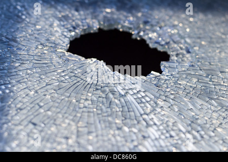 Trou dans un verre avec toutes les fissures créées Banque D'Images
