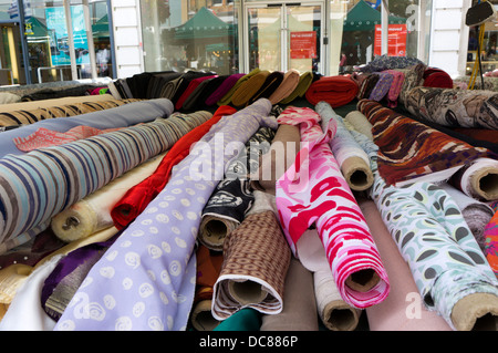 Rouleaux de tissu de couleur à motifs sur un étal de marché. Banque D'Images