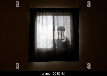 Un homme en regardant par la fenêtre. Banque D'Images