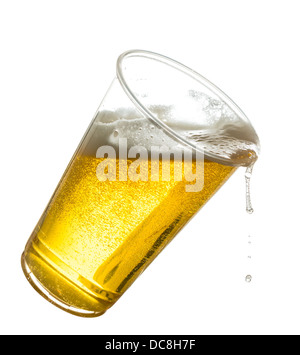 Lager Beer / inclinaison dans une pinte en plastique verre jetable déborder Banque D'Images