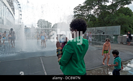 Femme touriste vue arrière photographier les enfants jouant dans une fontaine en été à l'extérieur du Royal Festival Hall Southbank Londres Banque D'Images