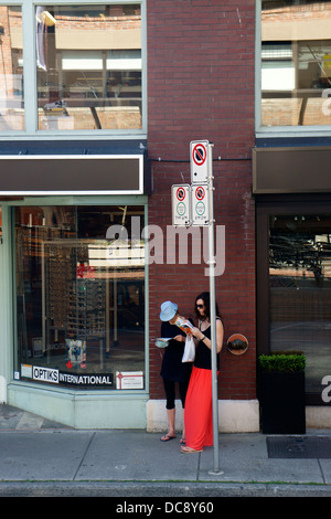 Deux jeunes femmes touristes lecture guides et cartes sur la rue de Yaletown, Vancouver, British Columbia, Canada Banque D'Images