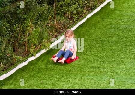 5 ans, fille, glissant sur une colline Banque D'Images