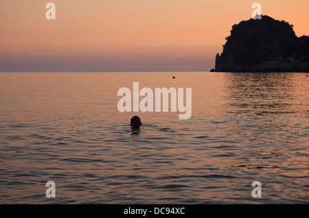 Nageur au coucher du soleil, dans la mer à Ermones sur l'île grecque de Corfou Banque D'Images