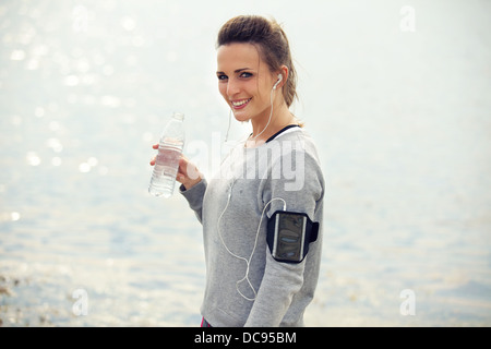 Happy female runner smiling while holding a l'eau en bouteille Banque D'Images