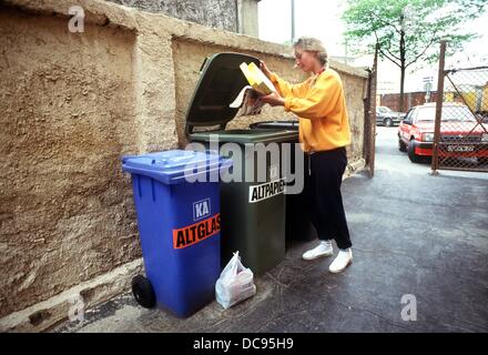 Une jeune femme se jette dans le papier des catalogues anciens bank devant sa maison en mai 1987. Les ménages de Frankfurt disposent d'un conteneur pour déchets de verre et déchets résiduels à leur disposition. Banque D'Images