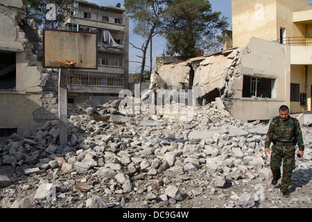 Une chasse de l'armée passe devant une école endommagée bombe dans Aleppo. Banque D'Images