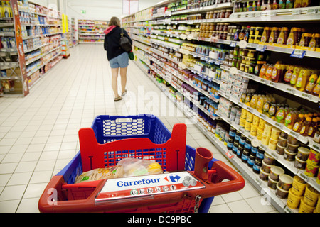 Une femme des courses dans l'allée d'un supermarché français Carrefour, France Europe Banque D'Images