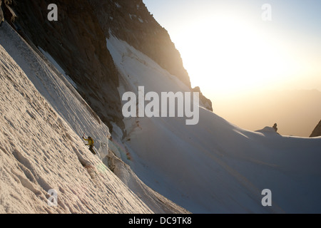 Escalade Alpinisme pente de neige. soleil et snow crest est visible en arrière-plan. Banque D'Images