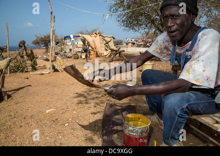 Artiste Amadou Dieng démontrant comment il travaille avec des objets trouvés et récupérés pour faire ses constructions. L'île de Gorée au Sénégal. Banque D'Images