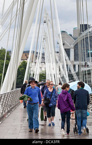 Touristes traversant la passerelle du Jubilé dans la pluie, Londres, Angleterre Banque D'Images