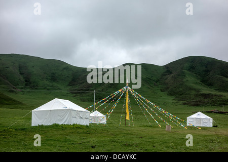 Drapeaux bouddhistes colorés et des tentes dans les montagnes, Sichuan, Chine Banque D'Images