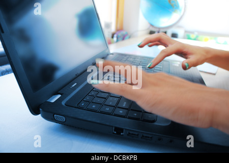Mains de femmes travaillant sur ordinateur portable sur fond de bureau Banque D'Images