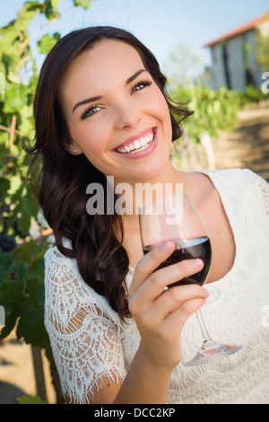 Jolie Mixed Race Woman buvant un verre de vin dans le vignoble. Banque D'Images