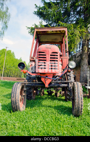 Vieux tracteur agricole rouge sur l'herbe dans farm Banque D'Images