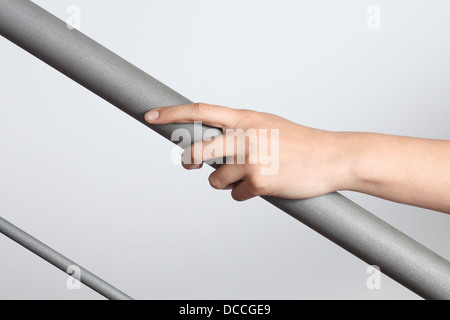 La femme à l'aide d'une rambarde d'aller à l'étage avec un fond gris clair Banque D'Images