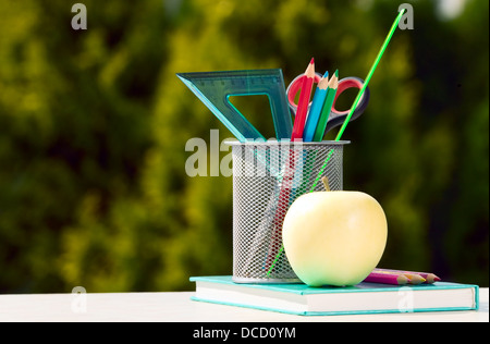 Outils pour l'école avec apple placé près sur fond vert Banque D'Images