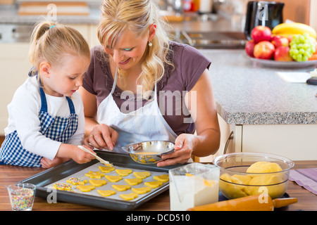 La cuisson avec la famille - Mère et fille coat self made cookies à l'aide d'un pinceau Banque D'Images