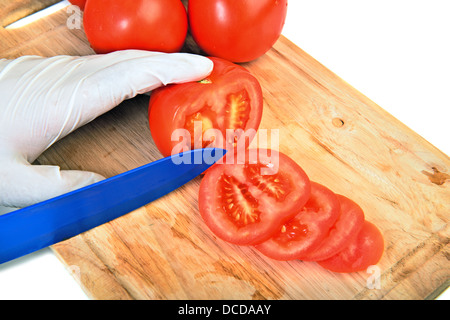 La tomate en tranches sur une planche à découper avec couteau en céramique sur fond blanc Banque D'Images