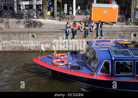 Groupe de jeunes gens qui regardent une excursion en bateau le long de la Korte Prinsengracht à Amsterdam, Hollande, Nentherlands. Banque D'Images