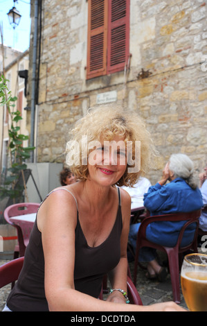 Woman sitting devant un bar à Puy L'Evêque dans le Lot Région ou département du sud ouest- Midi Pyrénées région de France Banque D'Images