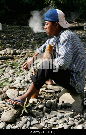 Man smoking pipe à eau, Laos Banque D'Images