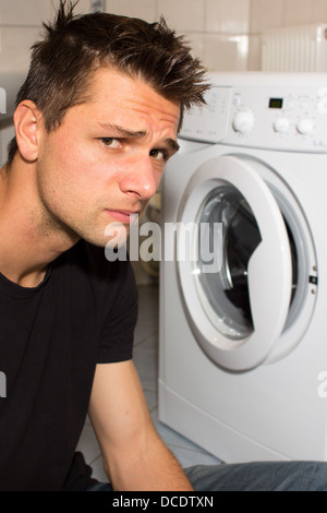 Jeune homme malheureux avec lave-linge Banque D'Images