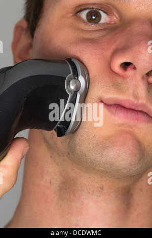 Man shaving face with electric razor Banque D'Images