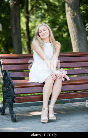 Jeune femme assise sur le banc dans le parc Banque D'Images