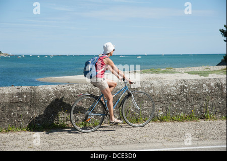Cycliste sur un pont sur la saire une rivière vers la mer à Reville Normandie France Banque D'Images