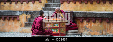 Deux moines assis ensemble à l'intérieur des murs de monastère de Séra, Lhassa, Tibet, Xizang, Chine Banque D'Images