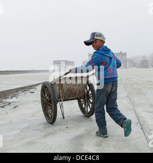 Garçon poussant deux-roues panier vers le bas ; passerelle Shannan, Tibet, Xizang, Chine Banque D'Images