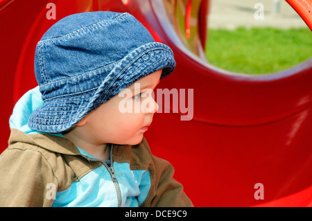 Un petit bébé garçon regarder d'autres enfants à jouer Banque D'Images