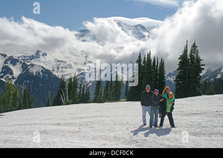 Une famille heureuse est situé sur un terrain couvert de neige devant le majestueux mont Rainier dans l'État de Washington, USA. Banque D'Images