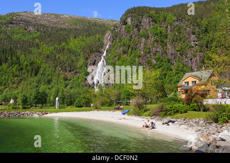 Cascade et plage avec les gens dans le village à la fin de l'Mofjorden pittoresque fjord. Mo, Modalen, Hordaland, Norvège, Scandinavie Banque D'Images