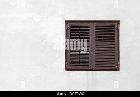 Fenêtre en bois avec jalousies fermées en mur blanc Banque D'Images