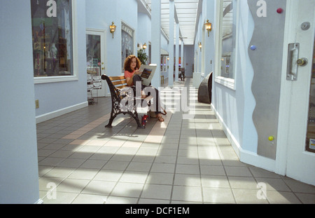Une jolie femme assise dans un intérieur commercial lit un journal dans la Virginia Highlands section d'Atlanta (Géorgie). Banque D'Images