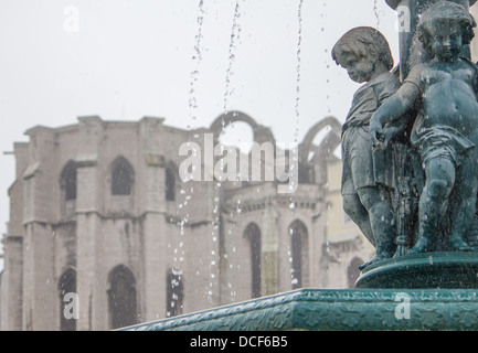 Fontaine de la place Rossio, à Lisbonne, avec les ruines du couvent de Carmo en arrière-plan. Banque D'Images