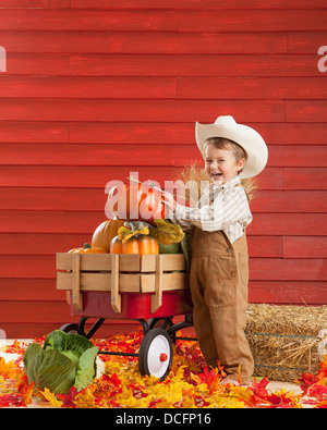 Un garçon vêtu comme un agriculteur avec un chariot plein de produire ; Three Hills, Alberta, Canada Banque D'Images