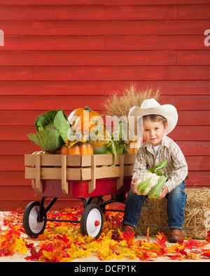 Un garçon vêtu comme un agriculteur avec un chariot plein de produire ; Three Hills, Alberta, Canada Banque D'Images