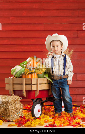 Un garçon vêtu comme un agriculteur avec un chariot plein de produire ; Three Hills, Alberta, Canada Banque D'Images