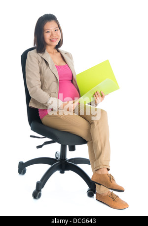 Corps plein six mois pregnant Asian businesswoman holding document dossier assis sur une chaise, isolé sur fond blanc. Banque D'Images