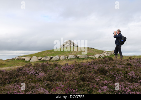 Homme male hiker walker à Penycloddiau avec des jumelles à l'âge de bronze des tumulus Flintshire Pays de Galles Cymru UK GO Banque D'Images