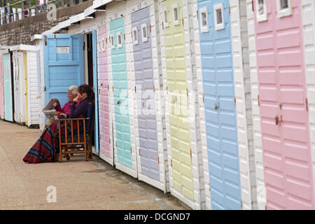 Lyme Regis, Dorset Royaume-Uni 17 Août 2013. Les touristes bravent le temps humide. Femmes assis à l'extérieur des cabanes de plage. Crédit: Carolyn Jenkins/Alay Live News Banque D'Images